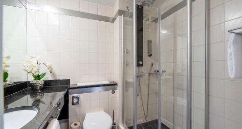 a bathroom with a shower and a toilet and a sink at PLAZA INN Stuttgart Airport Messe in Filderstadt