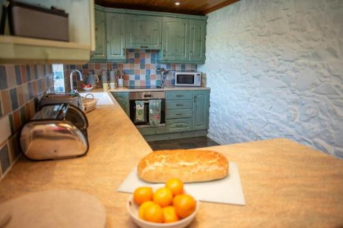 a kitchen with a counter with a loaf of bread and a bowl of oranges at Tan-yr-Onnen Llangrannog in New Quay