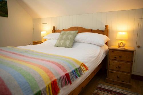 a bedroom with a large bed with a colorful blanket at Tan-yr-Onnen Llangrannog in New Quay