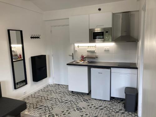 une cuisine blanche avec un évier et un micro-ondes dans l'établissement 2 pièces Gagny moins de 2 min du RER, à Gagny