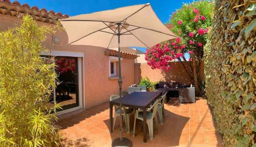 un patio avec une table et un parasol dans l'établissement Presqu'île de Giens, Joli T2 à 5 minutes de la plage à pieds, à Hyères