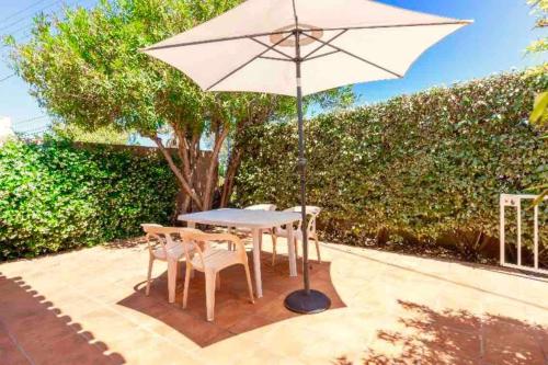 une table et des chaises avec un parasol sur une terrasse dans l'établissement Presqu'île de Giens, Joli T2 à 5 minutes de la plage à pieds, à Hyères
