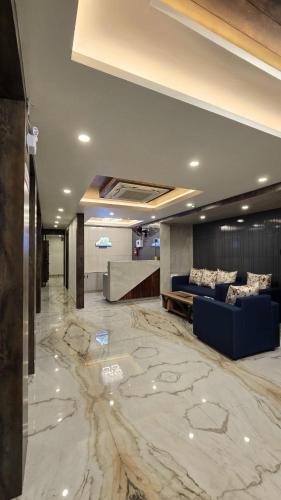 a lobby with a large marble floor and a blue couch at Hotel Akshaya in Port Blair