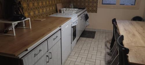 une cuisine avec des armoires blanches et un comptoir en bois dans l'établissement Chez Cécile et Sébastien, à Olliergues