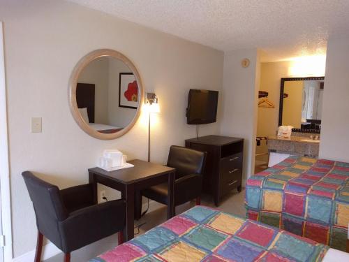 a hotel room with a desk and a bed and a mirror at Red Carpet Inn Airport Fort Lauderdale in Fort Lauderdale