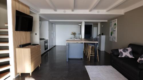 a living room with a couch and a kitchen at Maison pieds dans l'eau - Villa Veloutier in Saint-Paul