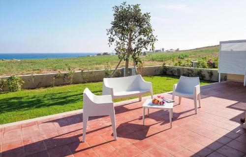 2 weiße Stühle und ein Tisch auf der Terrasse in der Unterkunft 2 Bedroom Lovely Home In Marina Di Modica in Marina di Modica