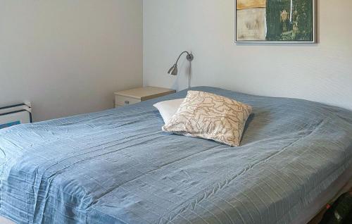 a bed with a blue blanket and a pillow on it at Gudhjem Søpark Lejl 47 in Gudhjem