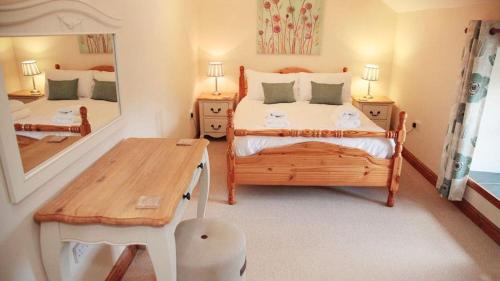 a bedroom with a bed and a table and a mirror at 3 Bed Cottage - Parking - Ideal for Work Trips in Swansea