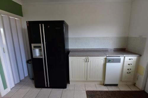 a kitchen with a black refrigerator and white cabinets at 2BD Garden Home - A Short Walk to Stonehenge in Lark Hill