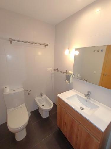a bathroom with a toilet and a sink and a mirror at Apartamentos Marina Suites in Grao de Castellón