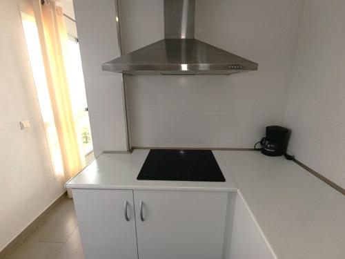 a small white kitchen with a stove top oven at Apartamentos Marina Suites in Grao de Castellón