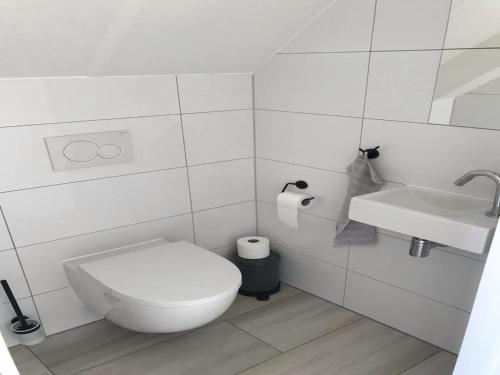 a white bathroom with a toilet and a sink at Beautiful Villa close to beaches in Sint Maarten
