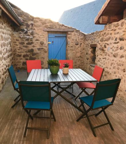 a wooden table with four chairs and a blue door at Gîte Chez Pyero in Aydat