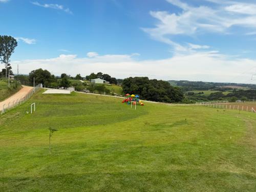 a large green field with umbrellas on it at Chalé Pôr do Sol in Contenda