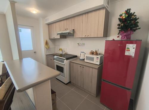 a kitchen with a red refrigerator and a christmas tree at Tranquilo y Hermoso Depto Nuevo - Valor INCLUYE IMPUESTO Y CARGOS in Villarrica