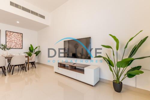 a living room with a tv and a potted plant at Special Rate with Temp Controlled Pool, BBQ & Maid's by Deluxe Holiday Homes in Fujairah