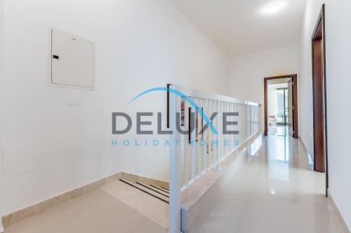 a white hallway with a sign that reads deluce holiday homes at Special Rate with Temp Controlled Pool, BBQ & Maid's by Deluxe Holiday Homes in Fujairah