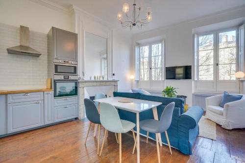 un salon avec un canapé bleu, une table et des chaises dans l'établissement MDOR Le Nid Bleu - Au coeur de Bordeaux, à Bordeaux
