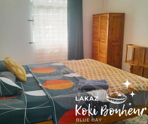 a bedroom with a bed with a blue blanket on it at Lakaz Koki Bonheur Blue Bay in Blue Bay