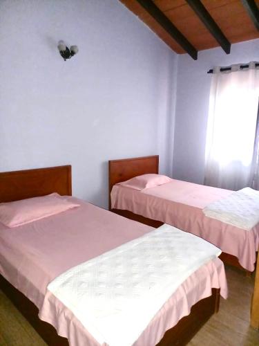 two beds in a room with a window at Casa con 2 habitaciones cerca del IPS central in Asunción