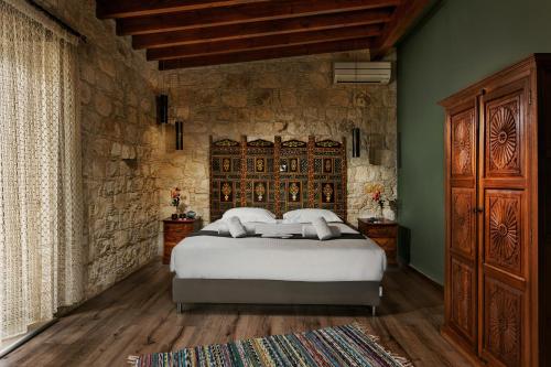 a bedroom with a bed and a stone wall at Oinoessa Traditional Boutique Guest Houses in Lofou