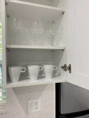 a shelf with cups and wine glasses on it at Newly renovated studio close to the beach in Hollywood