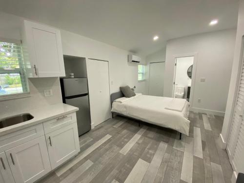 a white kitchen with a bed and a refrigerator at Newly renovated studio close to the beach in Hollywood