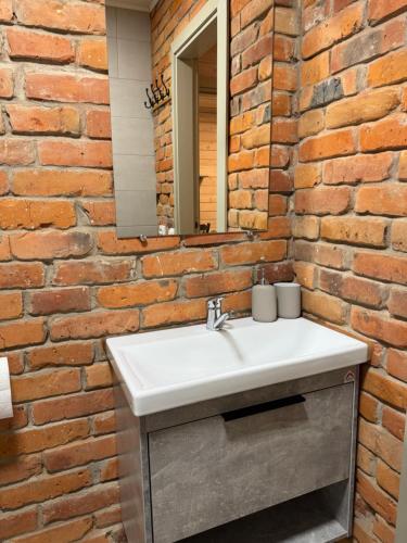 a bathroom with a white sink and a brick wall at Atostogų būstas in Kurėnai
