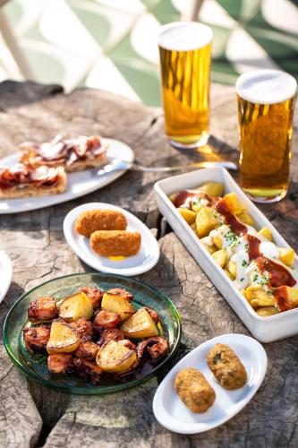 a table with plates of food and two glasses of beer at Radisson Blu 1882 Hotel, Barcelona Sagrada Familia in Barcelona