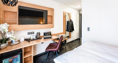 a bedroom with a desk with a bed and a tv at PLAZA INN Heilbronn in Heilbronn