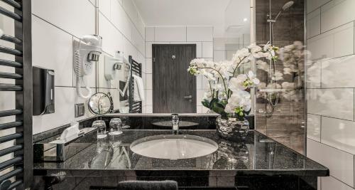 a bathroom with a sink and a vase of flowers at PLAZA INN Heilbronn in Heilbronn