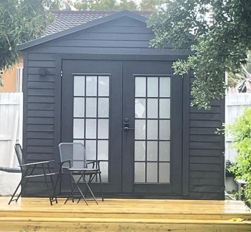 a black shed with a table and chairs on a deck at Charming Coastal Retreat in Miami