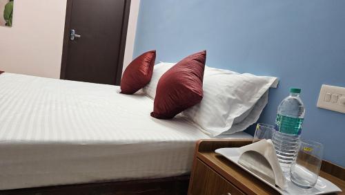 a bed with red pillows and a bottle of water at Pondy Pleasant Stay in Puducherry