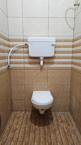 a bathroom with a white toilet in a stall at Pondy Pleasant Stay in Puducherry
