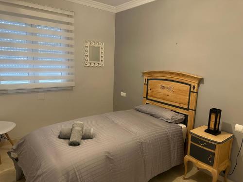 a bedroom with a bed with a wooden headboard and a window at GRAN ATICO MIJAS COSTA CoN PISCINA in Fuengirola