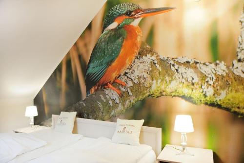 a colorful bird sitting on a tree branch at Malutkie Resort in Radomsko