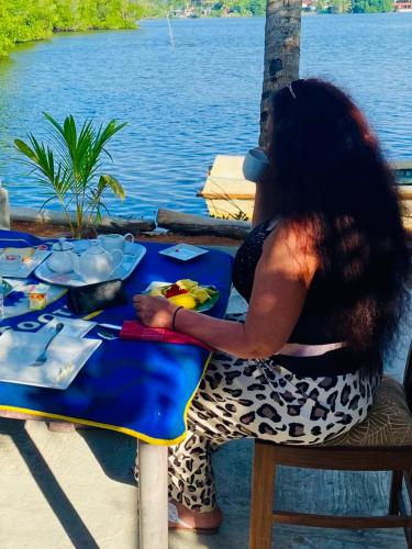 a woman sitting at a table near the water at Villa Roy Bentota in Bentota