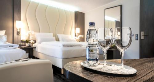 a hotel room with two wine glasses and a bottle of water at PLAZA INN Heilbronn in Heilbronn