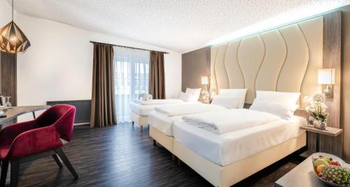 a hotel room with two beds and a desk at PLAZA INN Heilbronn in Heilbronn