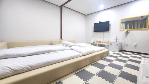 a bedroom with two beds and a tv on the wall at Kids & Family Hotel in Gyeongju