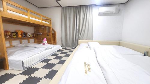 a bedroom with two bunk beds and a checkered floor at Kids & Family Hotel in Gyeongju