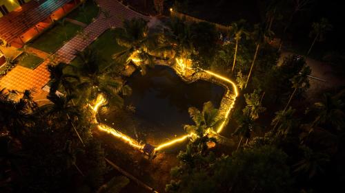 an aerial view of a pool at night with lights at Cocobaba Farmstay in Kumta