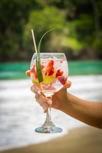 a hand holding a wine glass with fruit in it at Bungalows Beachfront Hotel in Punta Uva