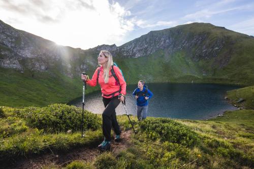 two women hiking on a hill near a lake at Appartements Mary inklusive Tauern-Spa Kaprun in Kaprun
