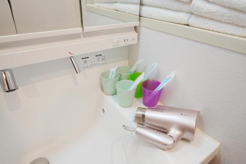 a bathroom with a sink with cups and toothbrushes at Near Skytree 90sqm 4BDR! 4mins to station! in Tokyo