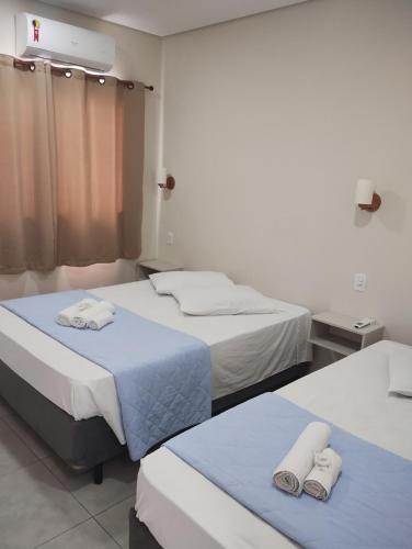 two beds in a hospital room with towels on them at Pousada Albamar Guarujá in Guarujá