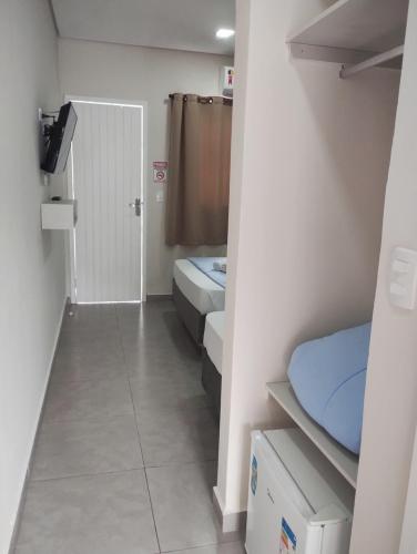 a small room with two beds and a bathroom at Pousada Albamar Guarujá in Guarujá