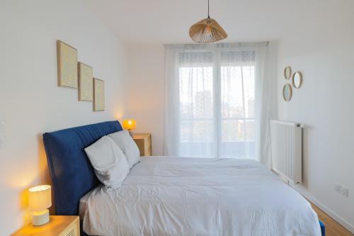 - une chambre avec un lit doté d'une tête de lit bleue et d'une fenêtre dans l'établissement Dolce Sarah, à Asnières-sur-Seine