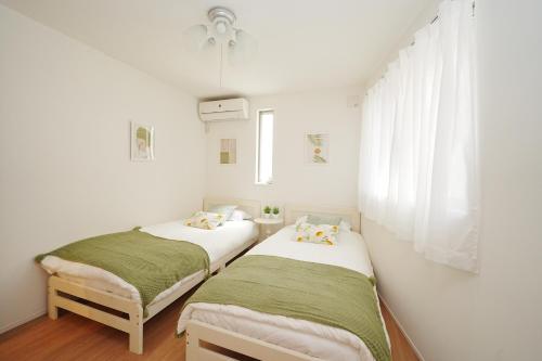 two beds in a room with white walls and a window at Near Skytree 90sqm 4BDR! 4mins to station! in Tokyo